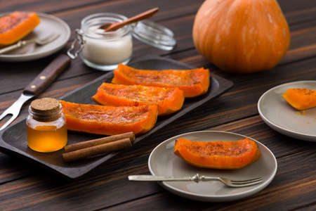 Baked slices of pumpkin with honey and sugar on wooden background. healthy dessert. selective focus.の写真素材