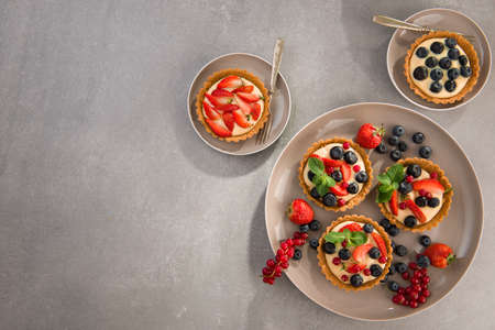 Mix berry tart, pie, with raspberries, bluberries, red currant and cream. on gray stone background. top view. copy space.の写真素材