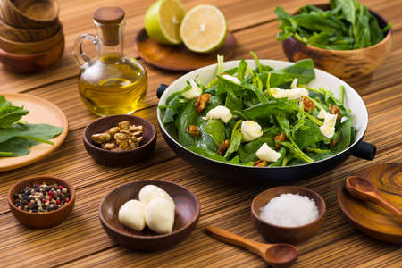 green salad with spinach caramelized walnut and feta cheese on wooden backgroundの写真素材