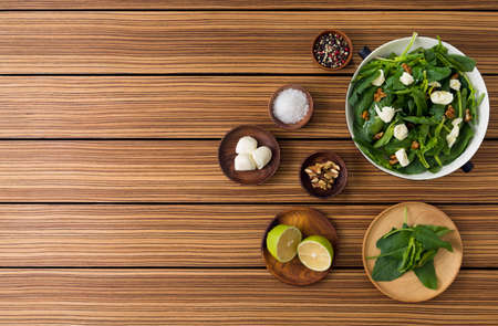 Green salad with spinach caramelized walnuts and feta cheese on wooden background. top view and copy space.の写真素材
