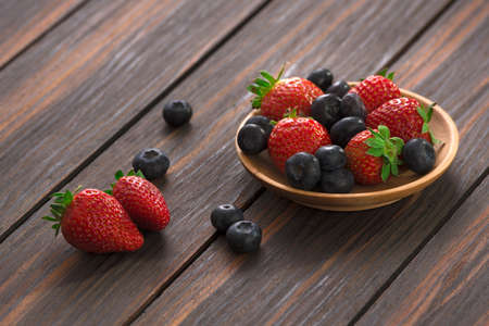 strawberry and blueberry in a wooden plate on wooden background.の写真素材