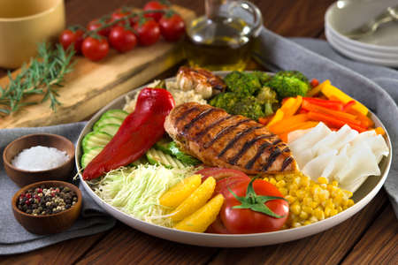 Healthy salad dish with grilled chicken, quinoa, garlic cabbage pepper bell, bell pepper orange, tomato, corn, barbecue. healthy eating. wooden background.の写真素材