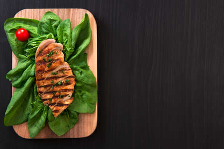grilled chicken breast on green leafs, healthy eating concept. dark wood background. top view. copy space.の写真素材