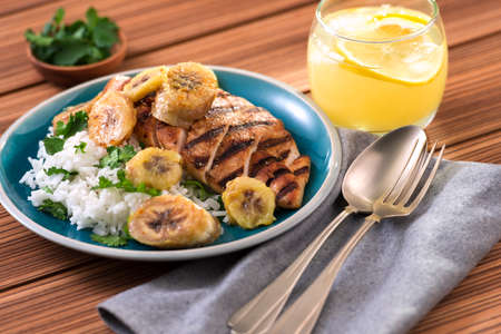 Grilled chicken with banana and rice on wooden backgroundの写真素材