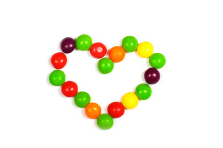 Heart made of colored smarties on a white background.の写真素材
