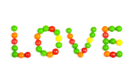 The word Love in capital letters spelled out on a white background using colorful candiesの写真素材