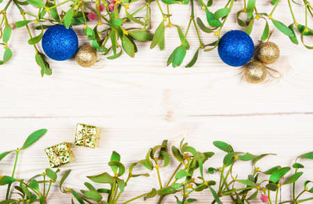 Christmas background border with gold bauble decorations, holly, mistletoe, fir and cedar cypress greenery on old parchment paper.の写真素材