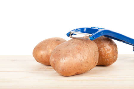 Potatoes, with a potato peeler, isolated on white backgroundの写真素材