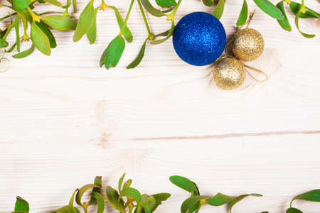 Christmas background border with gold bauble decorations, holly, mistletoe, fir and cedar cypress greenery on old parchment paper.の写真素材