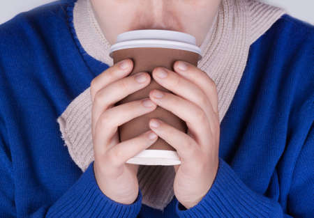Picture of a woman's hand holding a brown coffee cupの写真素材