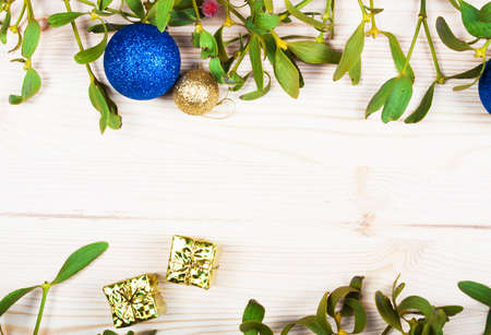 Christmas background border with gold bauble decorations, holly, mistletoe, fir and cedar cypress greenery on old parchment paper.の写真素材