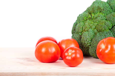 broccoli and tomatoes isolated on wooden tableの写真素材
