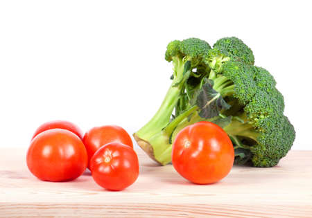broccoli and tomatoes isolated on wooden tableの写真素材