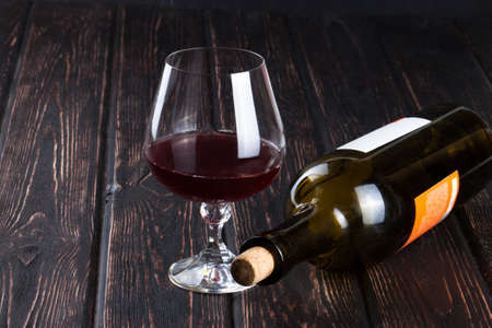 Black bottle of wine and wineglass on the wood backgroundの写真素材