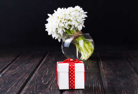 bouquet of snowdrops in vase and gift box on wooden boardsの写真素材