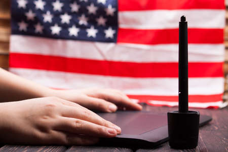 Hand is drawing on a digital graphic tablet with pen with american flagの写真素材