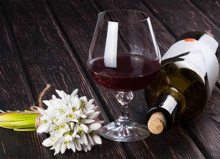 Black bottle of wine and wineglass and snowdrop on the wood backgroundの写真素材