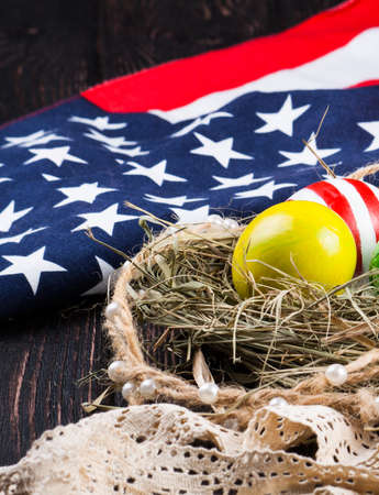 Easter eggs in the nest on rustic wooden background with american flagの写真素材