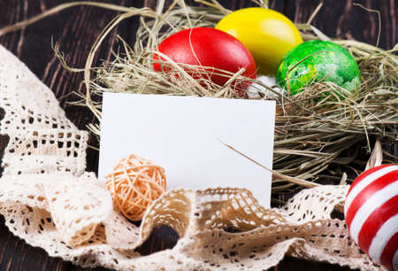 Easter eggs in the nest with card on rustic wooden backgroundの写真素材