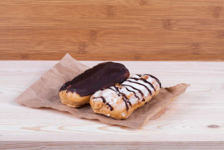 Eclairs glazed. Chocolate eclairs isolated on wood desk