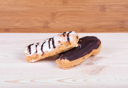Eclairs glazed. Chocolate eclairs isolated on wood desk