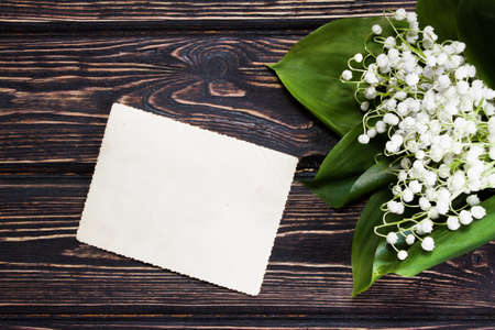 Beautiful floral frame with lilies of the valley flowers and clipboard on old wooden table.の写真素材