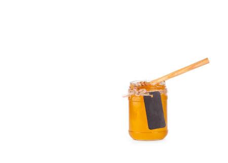 Jar of honey and  honey dipper on a white backgroundの写真素材
