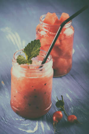 Retro photo with scratch texture. Watermelon smoothie in a jar on the boards with diced watermelon