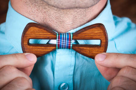 man wearing a wooden tie. the young guy putting on trendy wooden bow tie.のeditorial素材