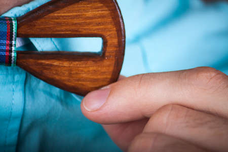 man wearing a wooden tie. the young guy putting on trendy wooden bow tie.のeditorial素材