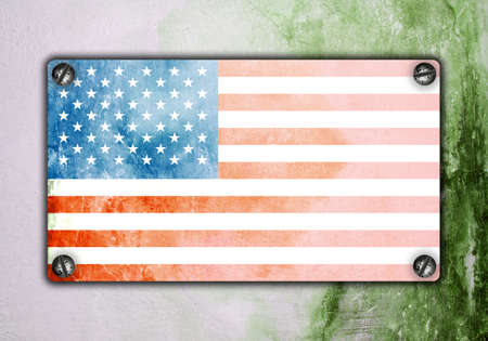 American flag on metal plate screwed screws on wall. Old grunge background