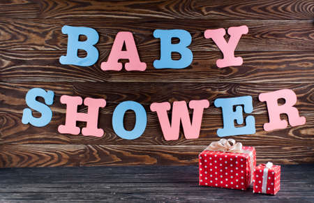 Decoration for Baby shower on wood desk. Color garland from infant shirt. Gift box