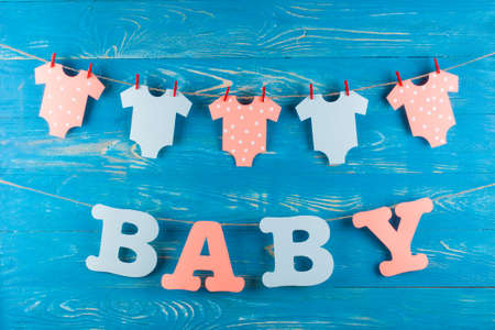 Decoration for Baby shower on wood desk. Color garland from infant shirt. Gift box