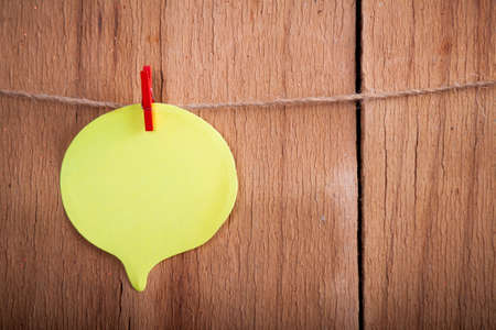 Yellow paper on rope on wood background. Place for textの写真素材