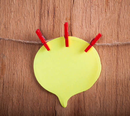 Yellow paper on rope on wood background. Place for textの写真素材