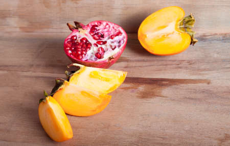 Photo ripe fresh pomegranate and persimmon on wood boardの写真素材
