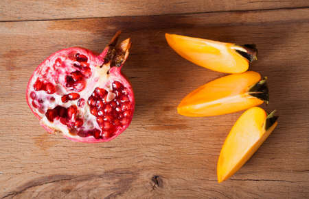 Photo ripe fresh pomegranate and persimmon on wood board.の写真素材