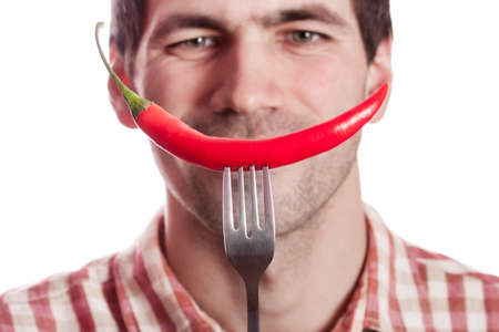 Young man having fun, holding red hot chilly pepper in mouth.の写真素材