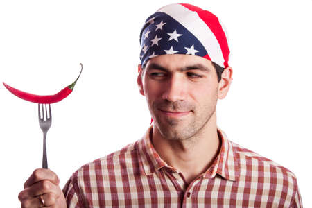 Young man having fun, holding red hot chilly pepper in mouth.の写真素材