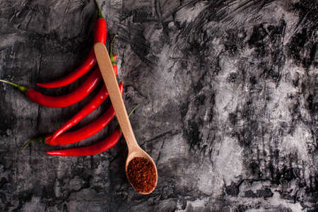 Spoon with seasoning chili and fresh chili on grunge dark background. Food backgroundの写真素材