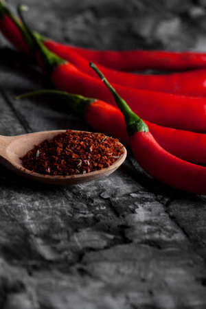 Spoon with seasoning chili and fresh chili on grunge dark background. Food backgroundの写真素材