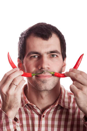 Young man having fun, holding red hot chilly pepper in mouth.の写真素材