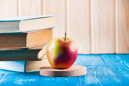 Stack of books and fresh apple on wood boardの写真素材