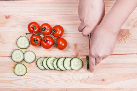 woman's hands cut cucumber on the board. Food backgroundの写真素材