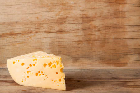 Piece of cheese close up on wood desk. Food background