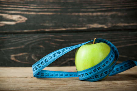 Fresh apple with measuring tape  on wood deskの写真素材