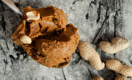 Peanut butter and roasted peanuts on wood deskの写真素材