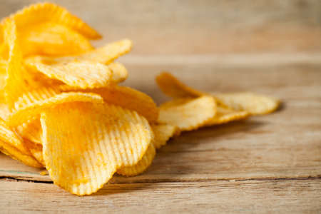 Fried potato chips corrugated on wood desk. Food