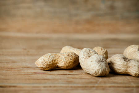 Roasted peanuts in shell close up on wood desk