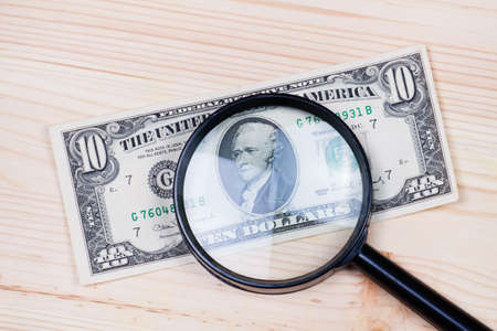 Dollar banknote and glass magnifying on wood desk.の写真素材